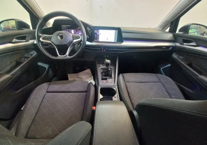 Intérieur avant de la Volkswagen Golf 2022, vue frontale sur tableau de bord noir avec écran tactile et volant multifonctions.