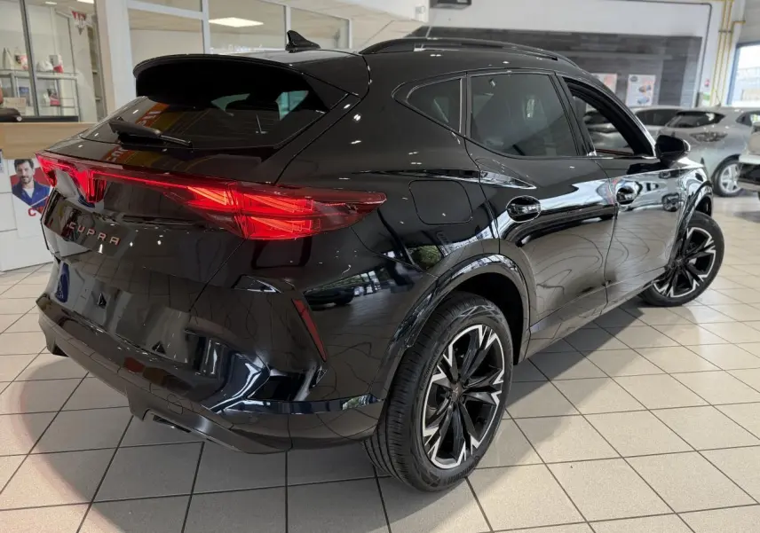Vue 3/4 arrière droite d'une CUPRA Formentor noire Night avec feux arrière Tri-LED et jantes alliage 18'' au showroom.