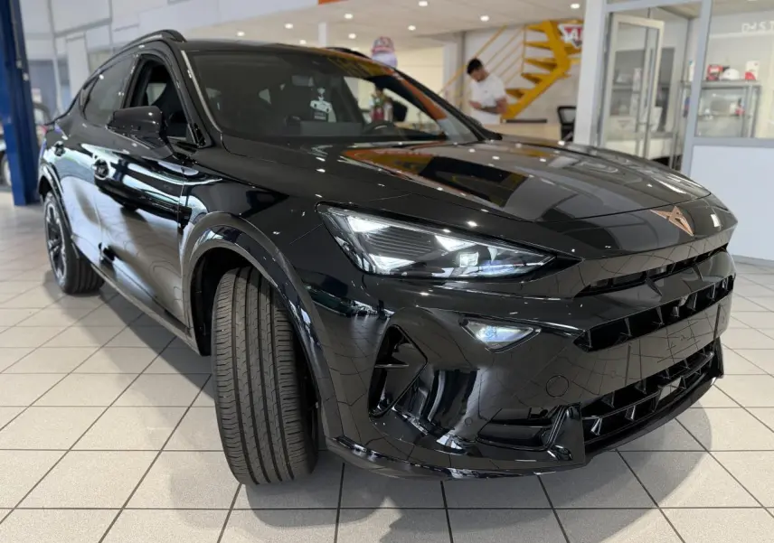 Vue 3/4 avant d'une CUPRA Formentor 2025 noir Night avec logo cuivré et jantes alliage 18'' en showroom.