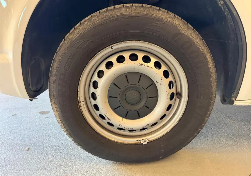 Gros plan sur la roue avant droite blanche du Volkswagen Transporter 2019 avec jante acier et logo VW central.