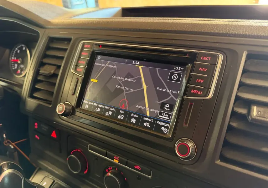 Vue intérieure du tableau de bord du Volkswagen Transporter blanc 2019, mettant en valeur l'écran GPS central et les commandes climatiques.