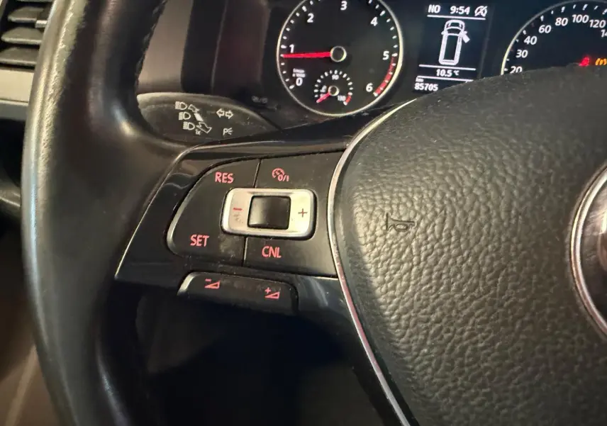 Gros plan sur le volant noir du Volkswagen Transporter 2019, avec commandes de régulateur de vitesse et tableau de bord en arrière-plan.