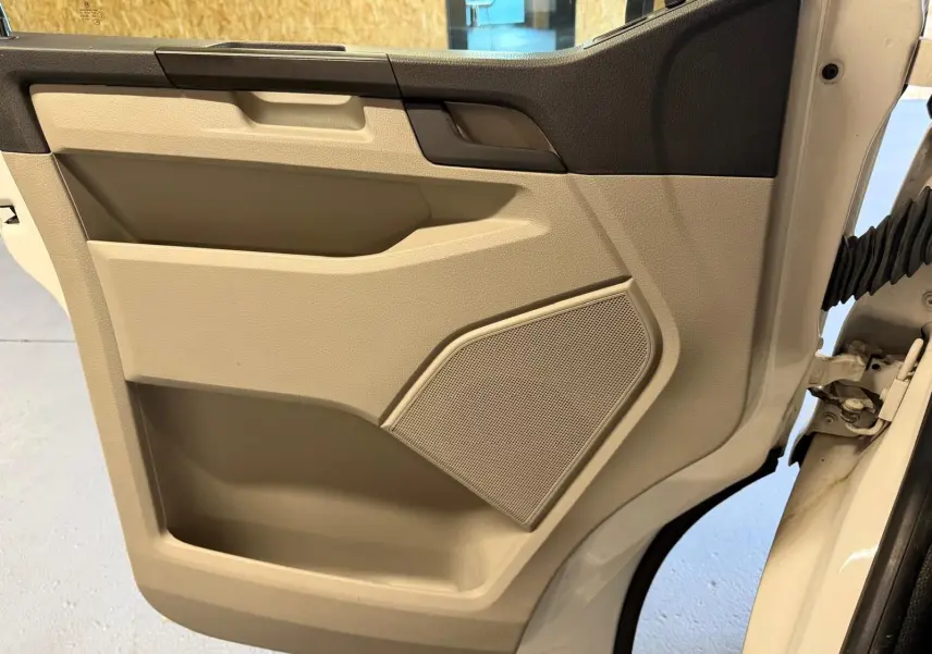 Vue rapprochée de la porte intérieure beige et noire côté droit du Volkswagen Transporter blanc de 2019.