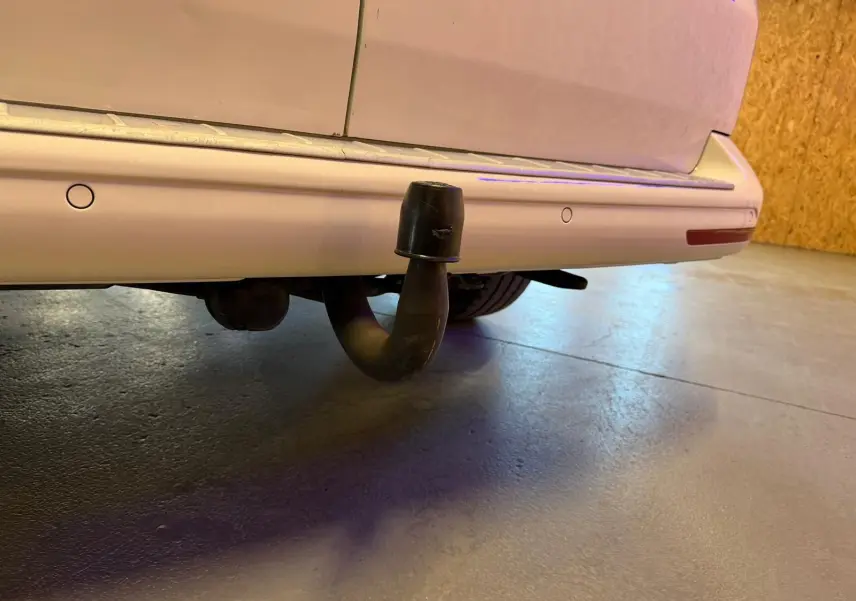 Vue rapprochée de l’arrière droit du Volkswagen Transporter blanc, mettant en valeur l’attelage de remorque.