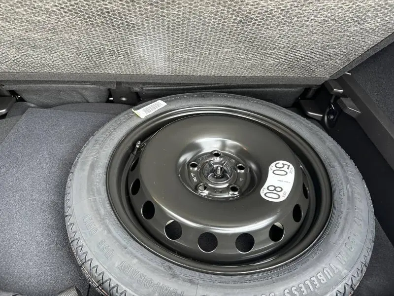 Pneu de secours noir dans le coffre d’un Renault Captur 1.8 E-Tech full hybrid 2026, vue de dessus.