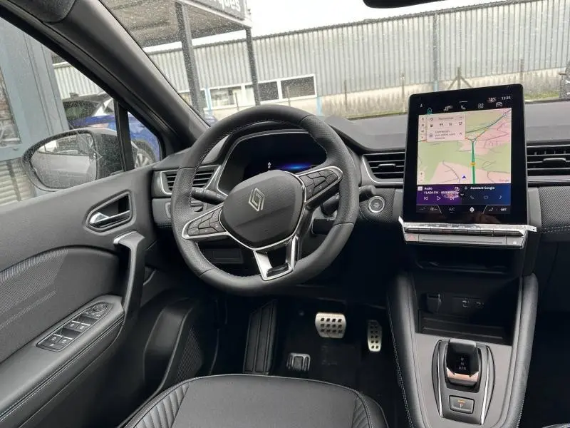 Vue intérieure côté conducteur du Renault Captur 2026, volant multifonction et écran tactile vertical avec navigation affichée.