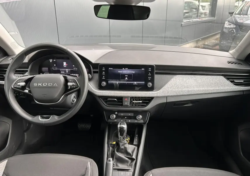 Vue intérieure frontale du tableau de bord de la Skoda Scala blanc Candy avec écran tactile et volant cuir multifonctions.
