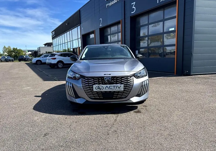 Peugeot 208 1.2 100 Allure gris Artense vue de face, calandre large et phares LED distinctifs visibles.