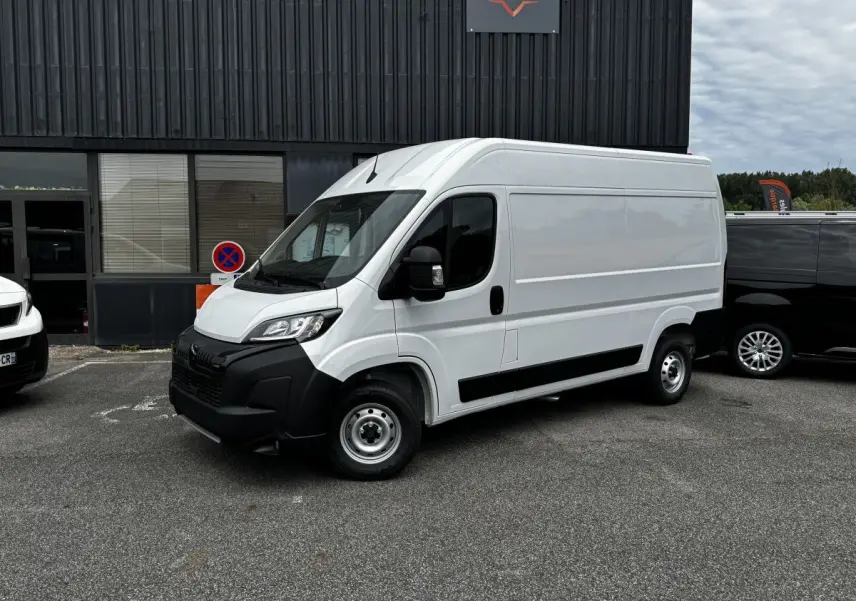 Peugeot Boxer Fourgon blanc en vue 3/4 avant droit, avec pare-chocs noirs et jantes acier simples.