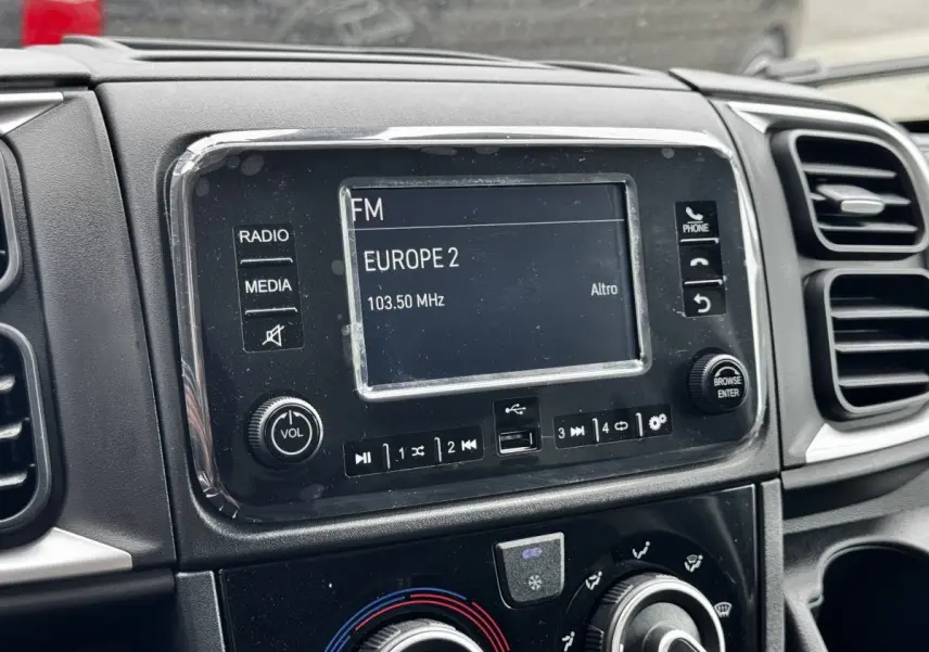 Gros plan sur l’écran tactile central du tableau de bord noir du Peugeot Boxer Fourgon blanc, affichant une radio FM.