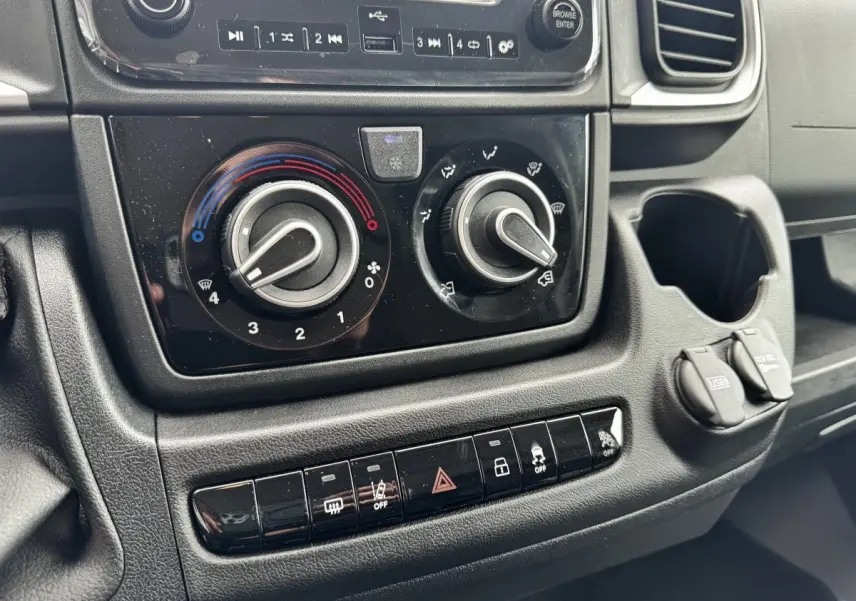 Gros plan sur la console centrale noire du Peugeot Boxer Fourgon blanc, avec commandes climatisation et ports USB visibles.