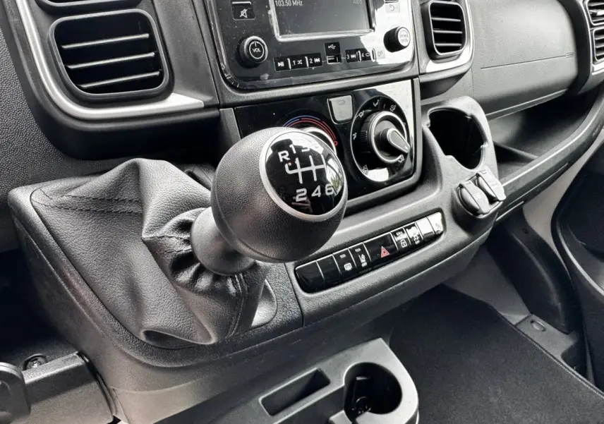 Gros plan sur la boîte manuelle et la console centrale noire du Peugeot Boxer Fourgon L2H2 2026, intérieur fonctionnel.