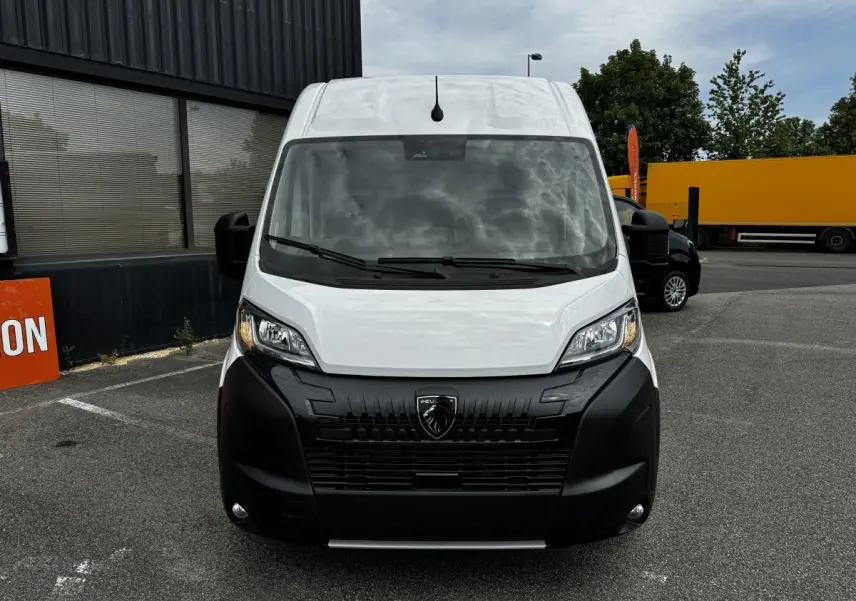Vue avant d’un Peugeot Boxer Fourgon blanc avec calandre noire et logo lion bien visible, stationné en extérieur.