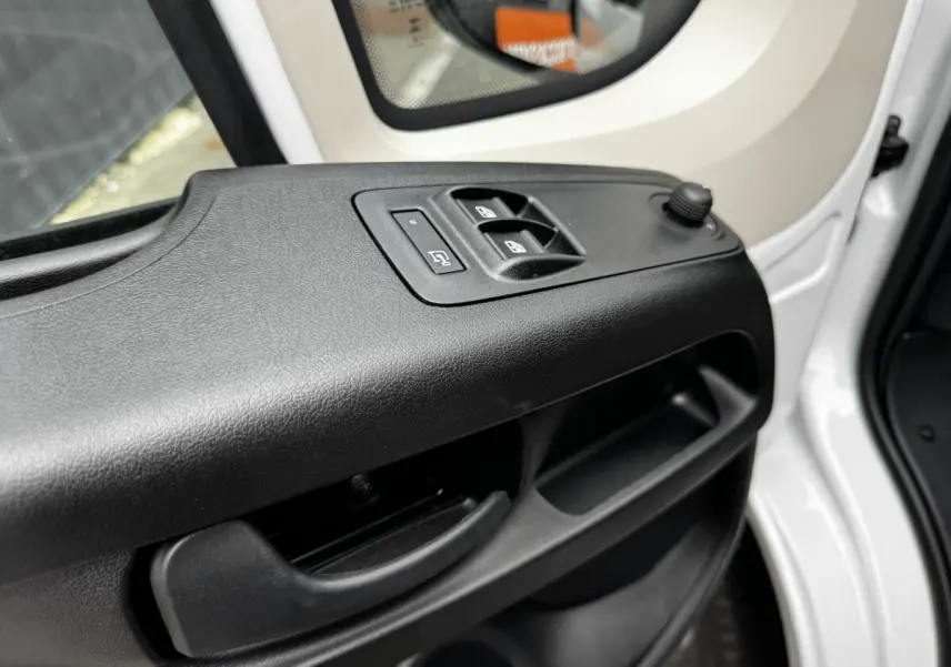 Gros plan sur la porte avant gauche blanche du Peugeot Boxer Fourgon, avec commandes électriques des vitres et rétroviseur.