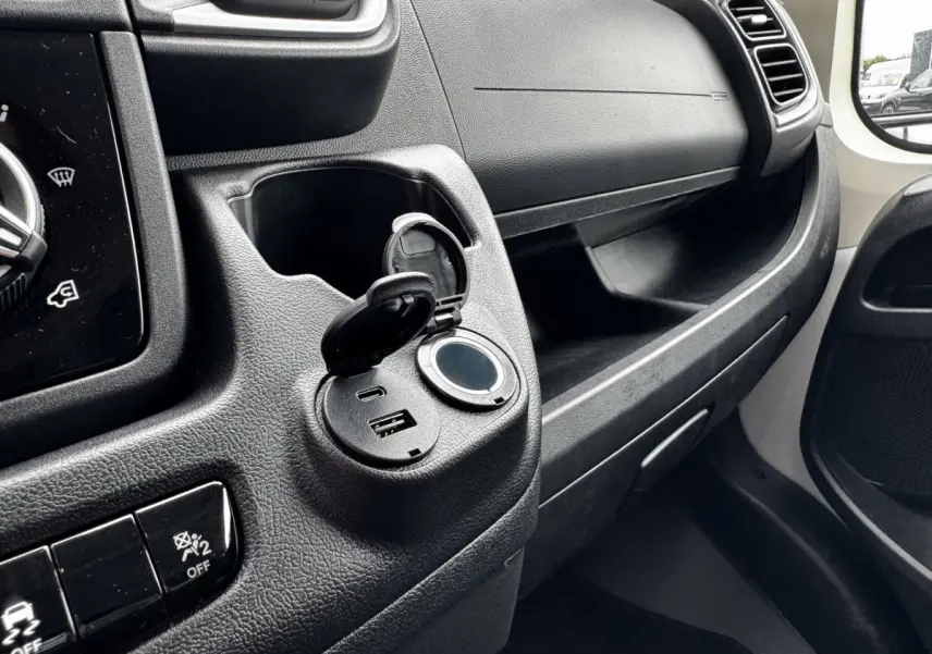 Vue intérieure côté passager du tableau de bord noir avec prise USB ouverte du Peugeot Boxer Fourgon blanc L2H2 2026.