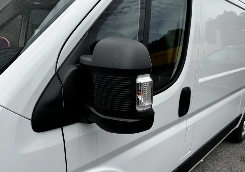 Gros plan sur le rétroviseur droit noir du Peugeot Boxer Fourgon blanc, côté conducteur, avec porte coulissante visible.