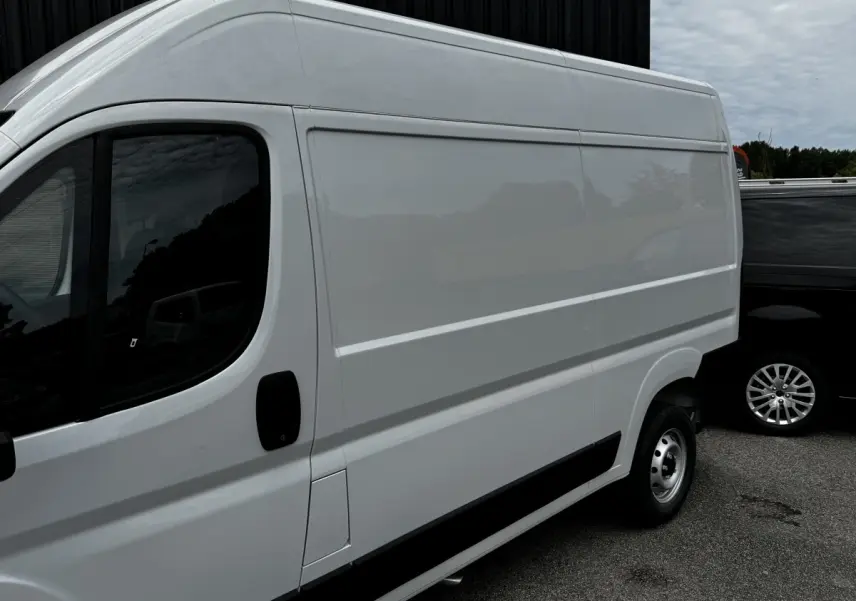 Vue de profil côté gauche d’un Peugeot Boxer Fourgon blanc, avec porte latérale coulissante et jante acier simple.