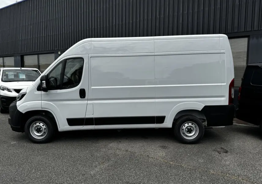 Vue de profil côté gauche d’un utilitaire Peugeot Boxer Fourgon blanc, version L2H2, avec protections noires sur les bas de caisse.