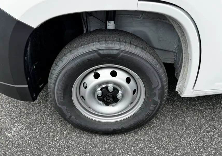 Gros plan sur la roue avant gauche du Peugeot Boxer Fourgon blanc, jante acier avec logo Peugeot central.