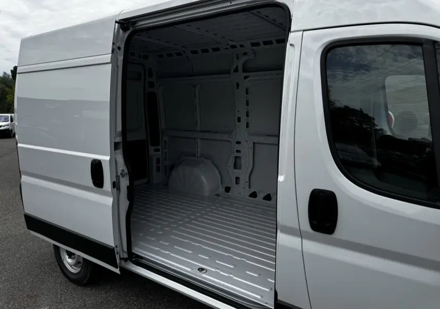 Vue latérale droite d’un Peugeot Boxer Fourgon blanc avec porte coulissante ouverte montrant l’espace de chargement vide.