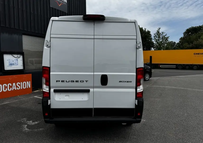 Vue arrière d’un Peugeot Boxer Fourgon blanc, avec portes battantes fermées et feux arrière rouges visibles.