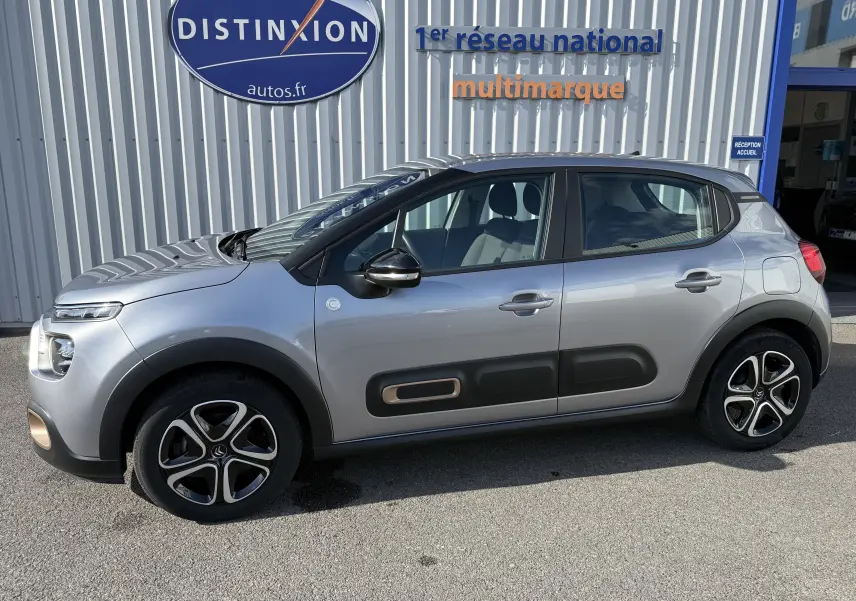 Profil côté gauche d'une Citroën C3 gris acier 2023 avec protections latérales noires et jantes stylisées.