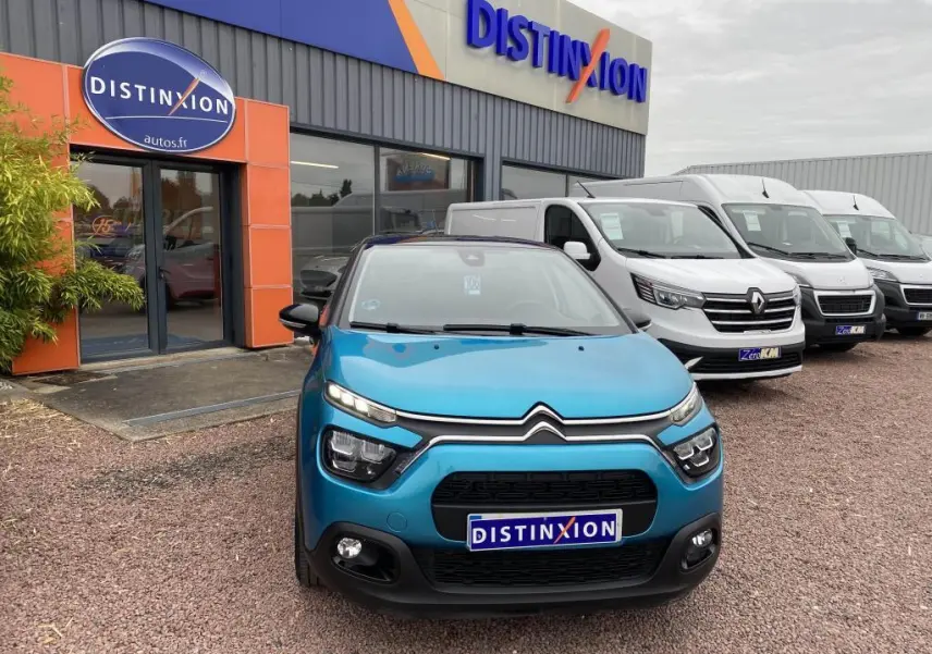 Vue frontale d'une Citroën C3 2023 bleu Spring Azul avec toit noir, devant un concessionnaire Distinxion.