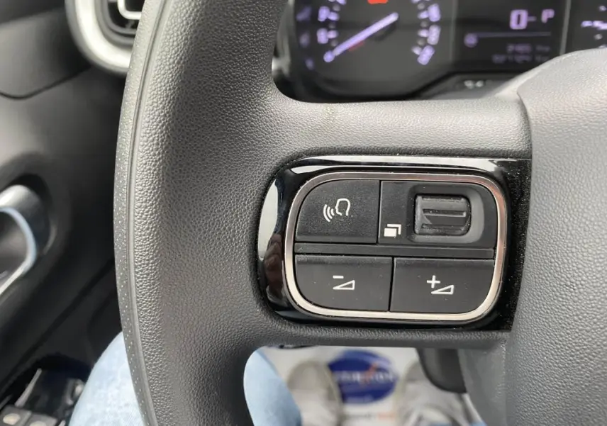 Gros plan sur les commandes audio au volant de la Citroën C3 2023, finition Shine, tableau de bord en arrière-plan.