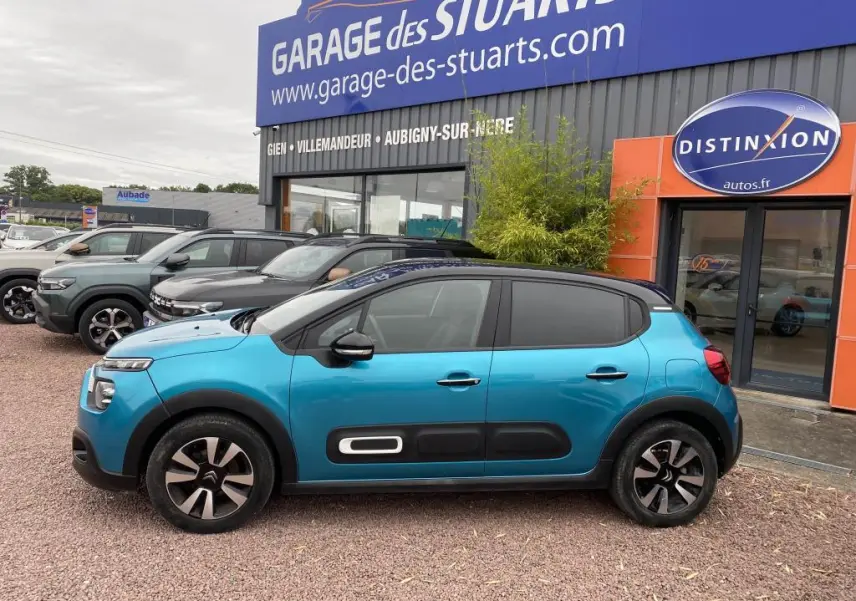 Citroën C3 2023 bleu Spring Azul avec toit noir, vue de profil côté gauche devant un garage.