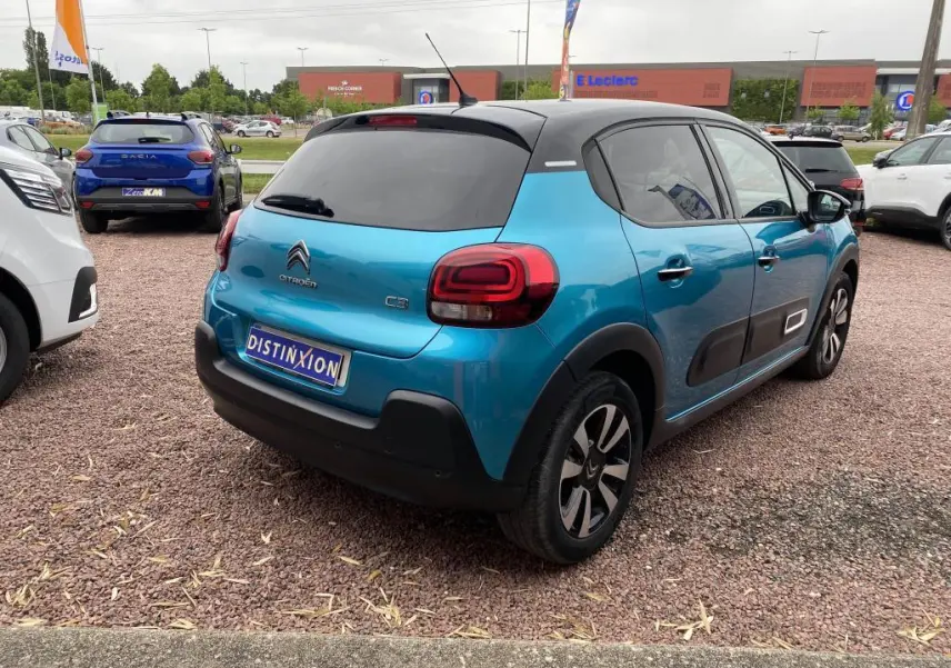 Vue 3/4 arrière droite d'une Citroën C3 2023 bleu Spring Azul avec toit noir et protections latérales noires.