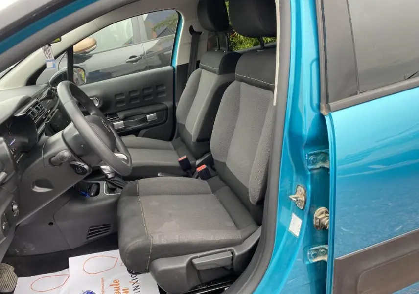 Intérieur avant côté conducteur d'une Citroën C3 2023 bleu Spring Azul, sièges tissu gris et tableau de bord noir.