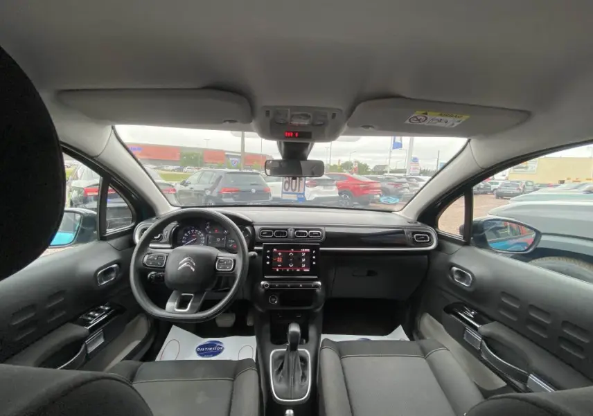 Vue intérieure frontale du poste de conduite d'une Citroën C3 2023 avec tableau de bord moderne et écran tactile central.