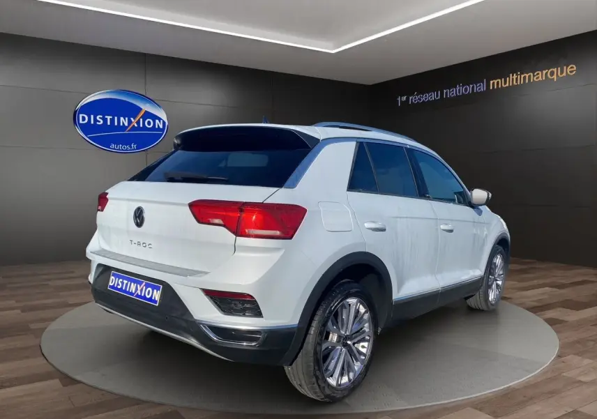 Volkswagen T-Roc blanc argenté vu en 3/4 arrière droit dans un showroom avec jantes alu 18 pouces.