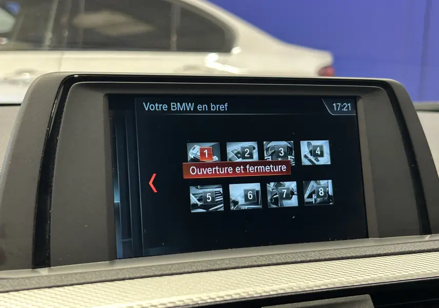 Écran central de BMW Série 1 120iA blanc affichant le menu « Ouverture et fermeture » avec interface tactile à 17h21.