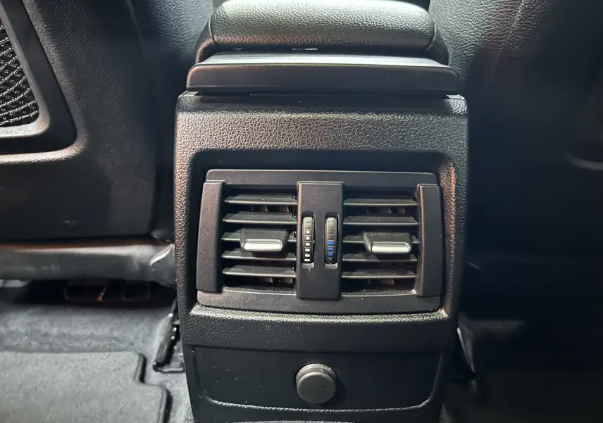 Gros plan sur la sortie d'air arrière noire du BMW Série 1 120iA M Sport blanc, avec commandes de ventilation visibles.