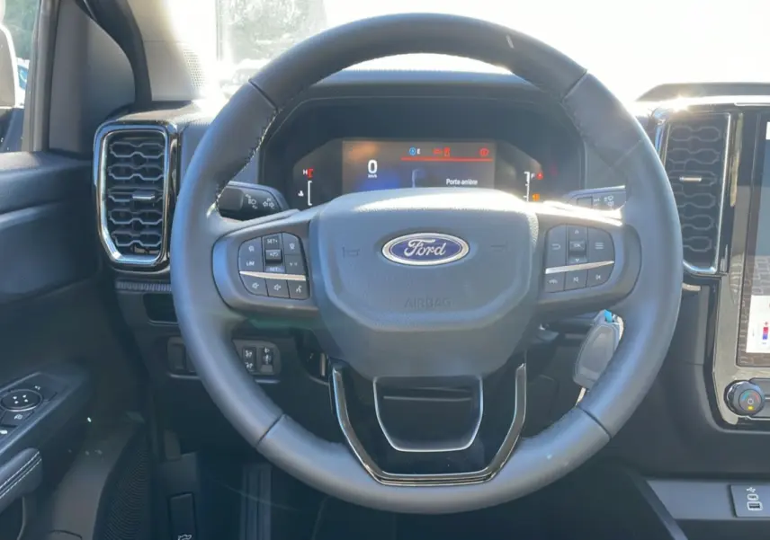 Vue rapprochée du volant noir du Ford Ranger 2025, avec tableau de bord digital et commandes intégrées visibles.