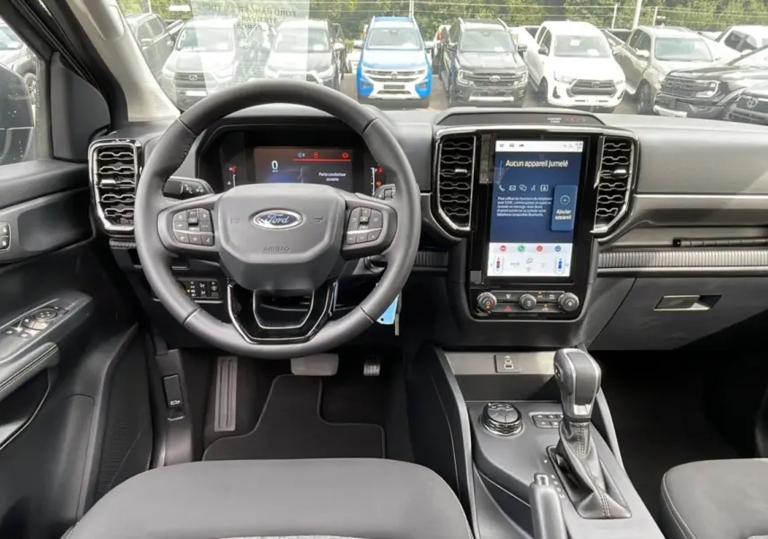Vue intérieure du Ford Ranger 2025 gris iconic, tableau de bord moderne avec écran tactile vertical et volant multifonction.