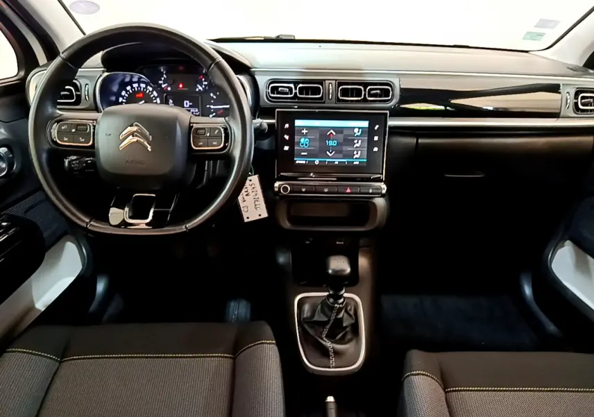Vue intérieure avant du tableau de bord noir et gris de la Citroën C3 avec volant cuir et écran tactile central.