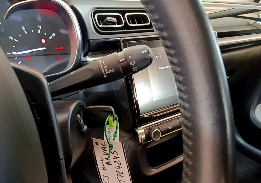 Vue rapprochée du tableau de bord et volant cuir noir de la Citroën C3 blanche avec écran tactile central allumé.