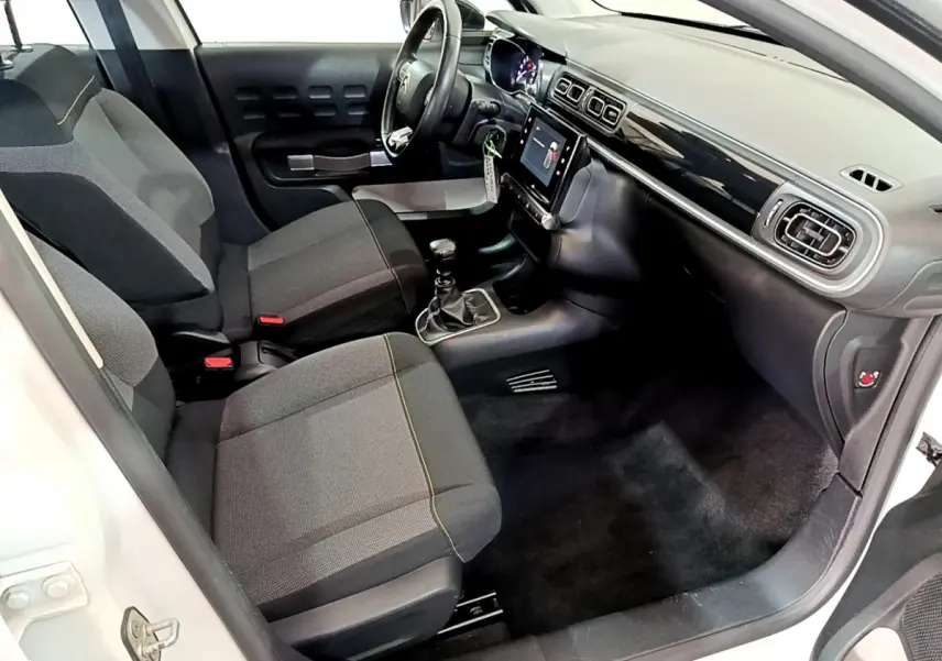 Intérieur avant droit de la Citroën C3 blanche 2019, montrant sièges tissu, tableau de bord avec écran tactile et volant cuir.