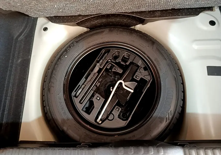 Gros plan sur la roue de secours noire dans le coffre blanc d'une Citroën C3 blanche de 2019.