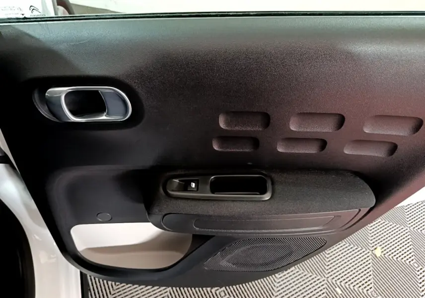 Gros plan sur la porte côté gauche blanche et noire de la Citroën C3 PureTech 110 Shine Business 2019, avec poignée et commande fenêtre.