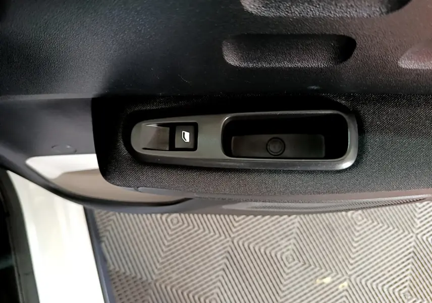 Gros plan sur la commande de lève-vitre côté gauche de la porte intérieure d'une Citroën C3 blanche de 2019.