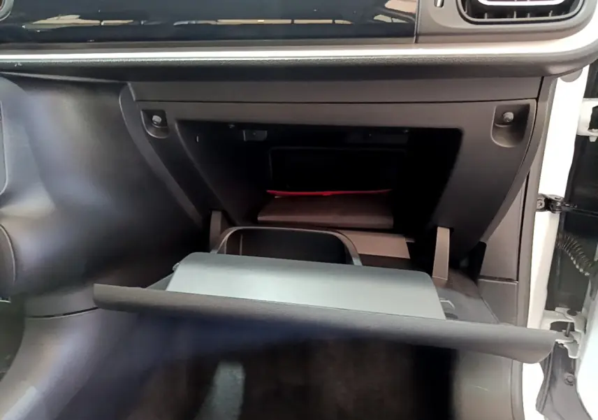 Gros plan sur la boîte à gants ouverte côté passager de la Citroën C3 blanche, intérieur noir.