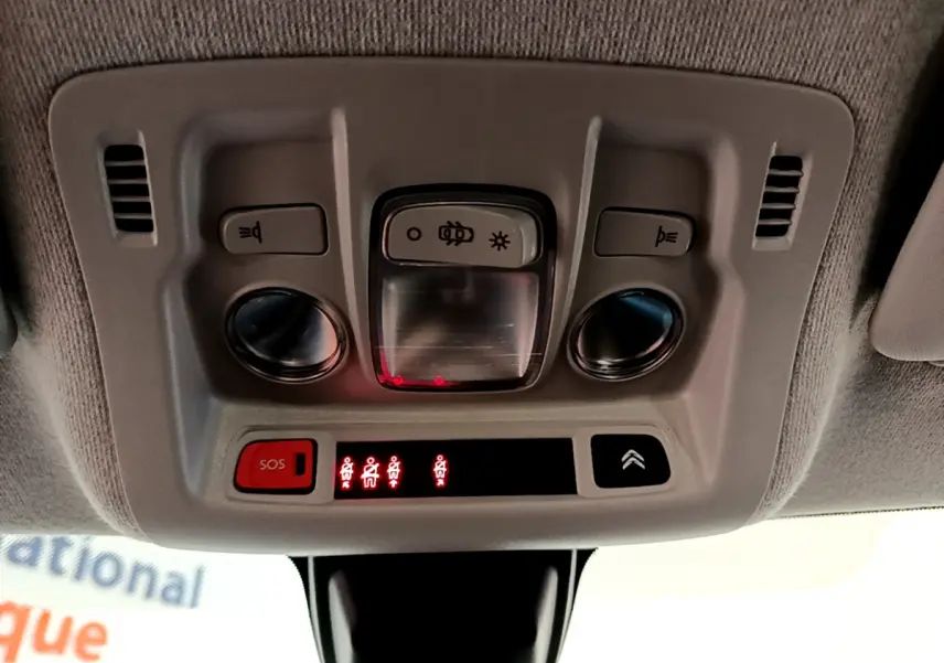 Vue en gros plan du plafonnier intérieur avec commandes d'éclairage et bouton SOS de la Citroën C3 blanche de 2019.
