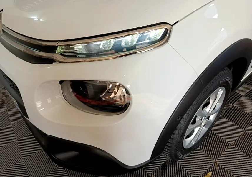 Gros plan sur l'avant droit blanc d'une Citroën C3 2019, mettant en valeur ses phares LED et la roue en jante alliage.