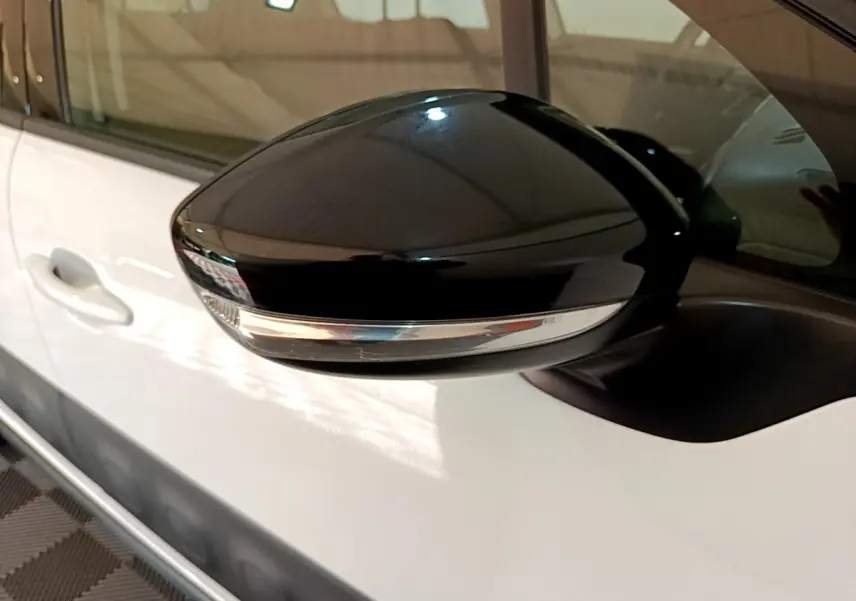 Rétroviseur noir avec clignotant intégré côté gauche d'une Citroën C3 blanche vue de près.