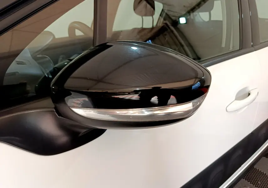 Rétroviseur noir brillant côté gauche d'une Citroën C3 blanche, avec clignotant intégré visible.