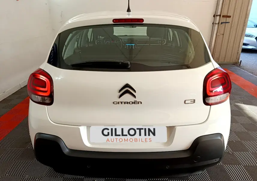 Vue arrière d'une Citroën C3 blanche 2019 avec feux arrière allumés et logo centré sur un sol à damiers.