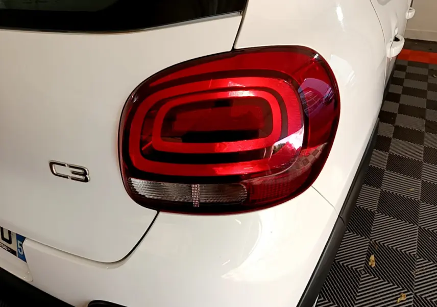 Feu arrière droit et logo C3 sur la partie arrière blanche d'une Citroën C3 PureTech 110 de 2019.